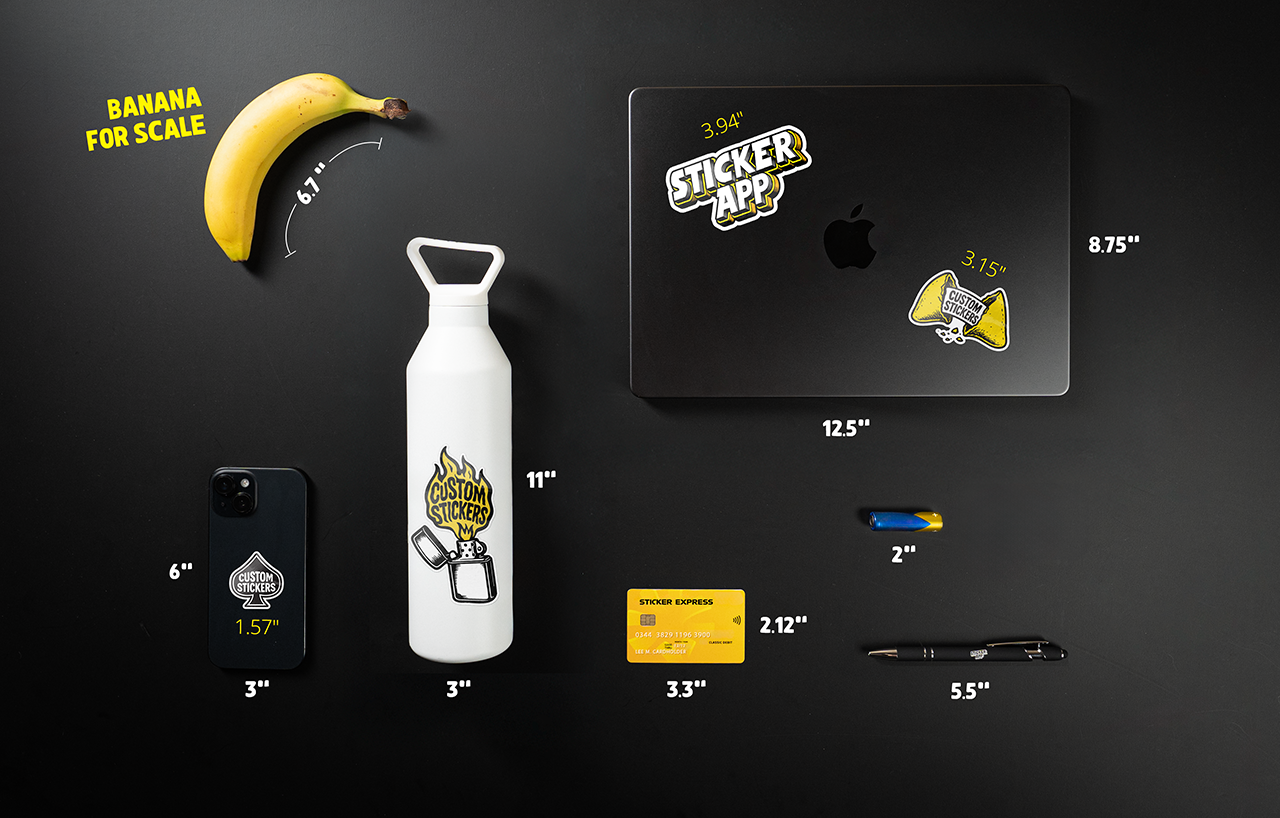 Size guide for stickers. A flat lay of various items on a black surface, including a banana, laptop, water bottle, phone, card, pen, cutter, and stickers, with measurements.