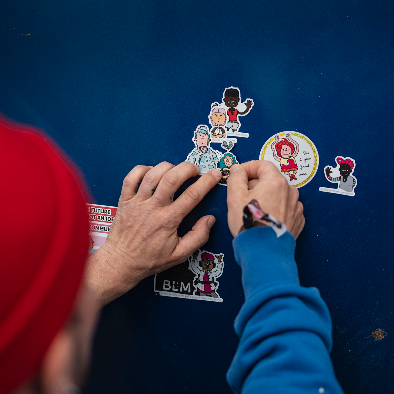 Die-cut stickers printed in various materials and sizes slapped on a dark blue wall.