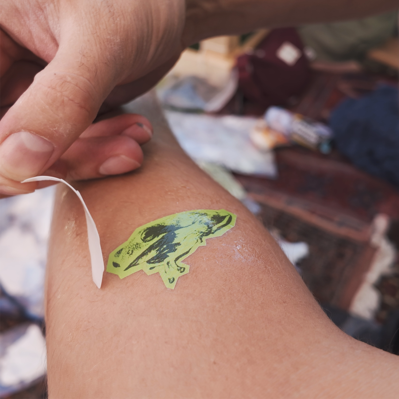 Die-cut temporaty tattoo in light and dark green, placed on an arm with the backing film peeled