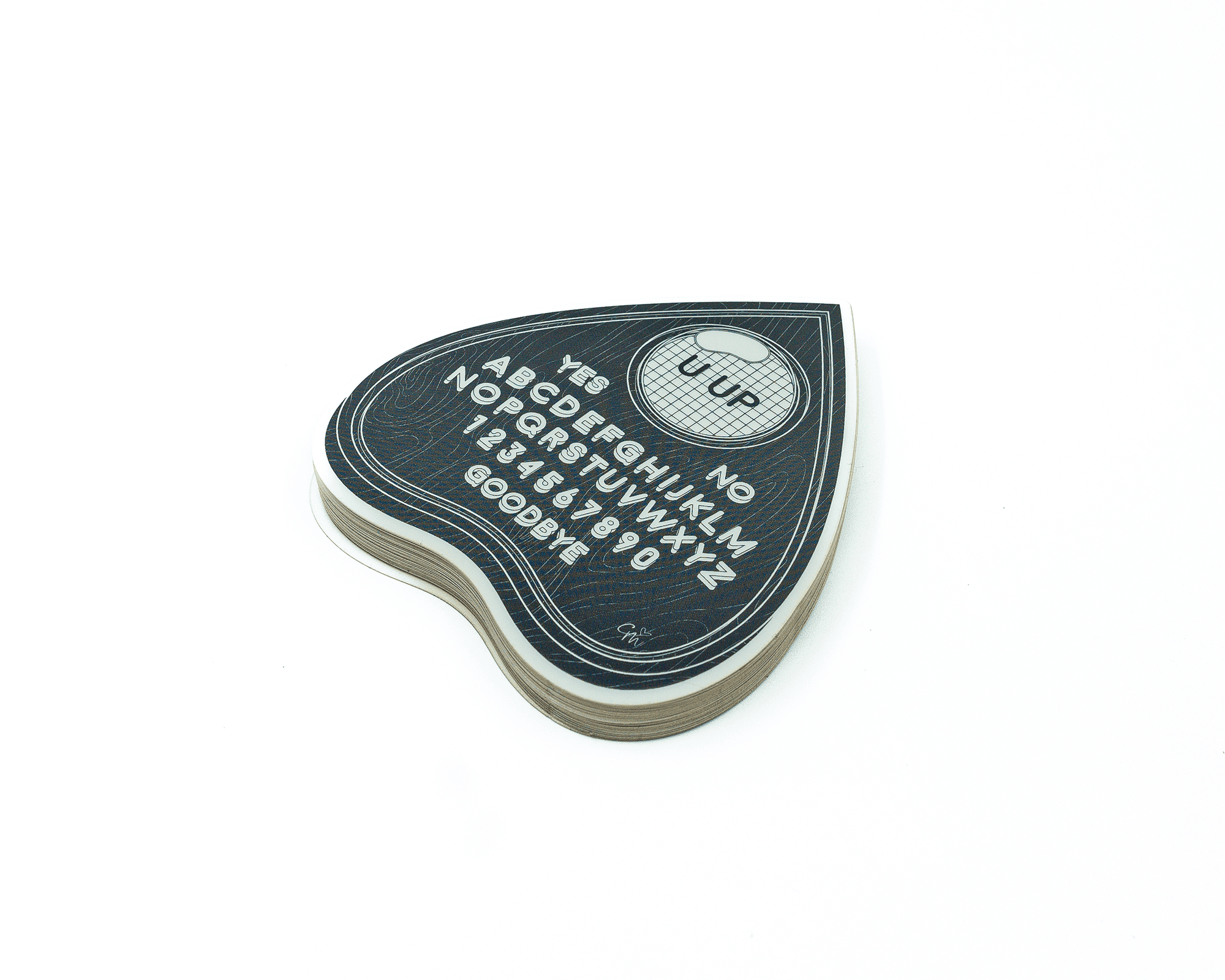 A stack of heart-shaped stickers resembling a Ouija board planchette, featuring letters, numbers, and "YES" and "NO" options.