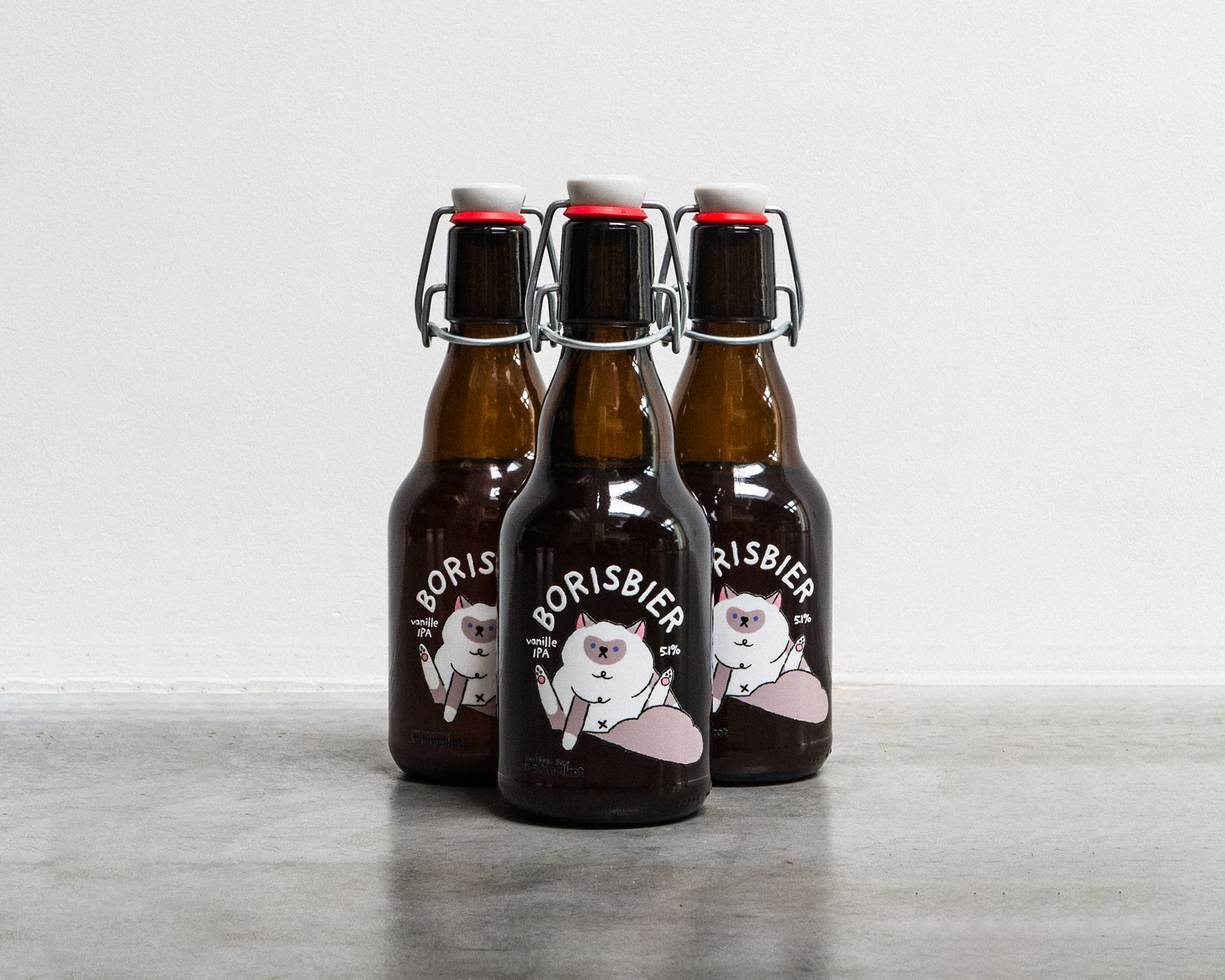 Three brown glass bottles of Borisbier with swing-top caps, featuring a cartoon bear uv transfer, are arranged on a gray surface.
